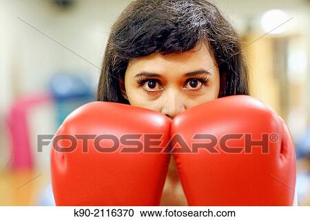 Stock Image - Asian woman hiding behind her big red boxing gloves, Jakarta, Indonesia, Southeast Asia.. Fotosearch