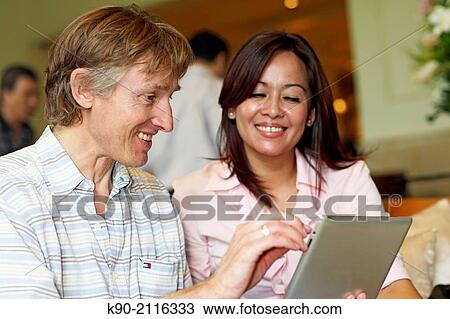 Asian women and Caucasian man holding a tablet computer, Jakarta, Indonesia, Southeast Asia. View Large Photo Image Stock Image - Asian women and Caucasian man holding a tablet computer, Jakarta, Indonesia, Southeast Asia.. Fotosearch