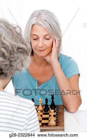 Beautiful mature woman playing chess with another senior woman View Large Photo Image Picture - Beautiful mature woman playing chess with another senior woman. Fotosearch