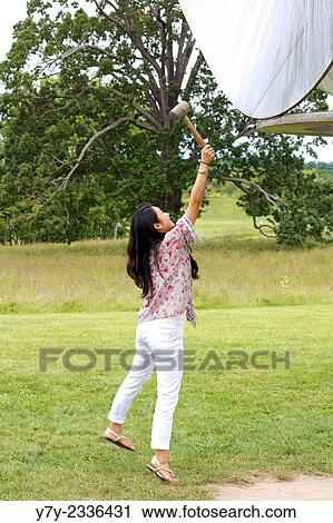 Beautiful young Asian woman jumps up to strike a giant gong with a rubber mallet. View Large Photo Image Stock Image - Beautiful young Asian woman jumps up to strike a giant gong with a rubber mallet.. Fotosearch
