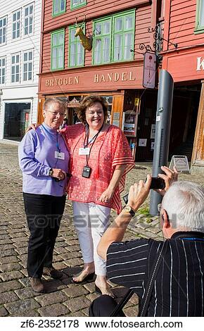 Bergen Norway Bryggen retired tourist woman taking photo in front of colorful old wooden houses and smiling selfie MR-12. View Large Photo Image Stock Photo - Bergen Norway Bryggen retired tourist woman taking photo in front of colorful old wooden houses and smiling selfie MR-12.. Fotosearch