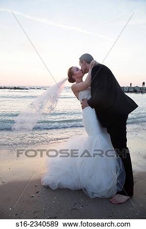 Bride and groom kissing on the beach on sunrise/ sunset background. View Large Photo Image Stock Photo - Bride and groom kissing on the beach on sunrise/ sunset background.. Fotosearch