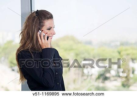 Stock Photography - Business woman talking on the phone and looking out the window. Fotosearch