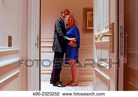 Stock Image - Caucasian man and woman holding each other in front of the door of a hotel room, Hotel Hermitage, Monte Carlo, Monaco, Europe.. Fotosearch