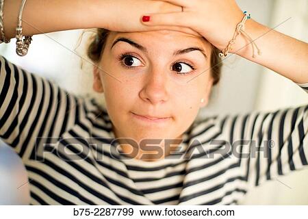 Stock Photo - Closeup of a teenage girl with her hands on her head and glancing with naughty expression. Fotosearch