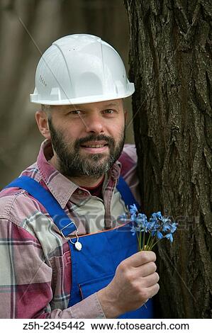 Stock Image - Construction worker with a bouquet of heather.. Fotosearch