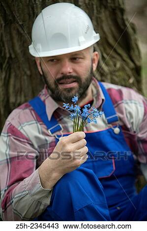 Stock Image - Construction worker with a bouquet of heather.. Fotosearch