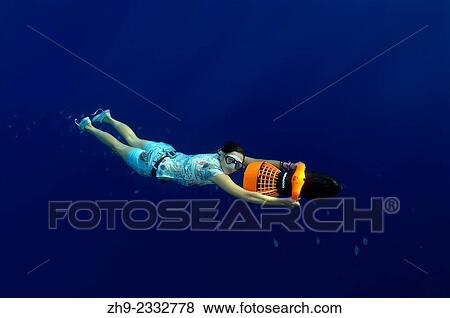 Freediver swims to underwater scooter, night diving in the Red Sea, Egypt. View Large Photo Image Stock Photo - Freediver swims to underwater scooter, night diving in the Red Sea, Egypt.. Fotosearch