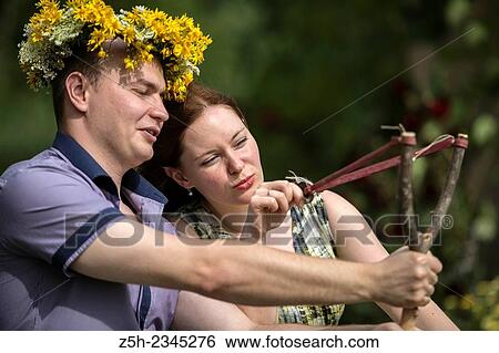 Stock Photograph - Lovers with wreaths on their heads retired in the park.. Fotosearch