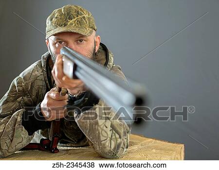 Stock Photo - Man in camouflage with shotgun. Fotosearch