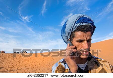 Morocco Sahara Desert sand dunes portrait of local man with turbin on cell phone in Las Palmeras area. View Large Photo Image Stock Photo - Morocco Sahara Desert sand dunes portrait of local man with turbin on cell phone in Las Palmeras area.. Fotosearch