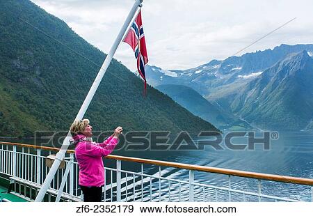 Norway cruise Hurtigruten ship fjord woman taking photo of scenic from balcony with old Norway Postal flag in Hjorundjorden MR-15. View Large Photo Image Stock Photo - Norway cruise Hurtigruten ship fjord woman taking photo of scenic from balcony with old Norway Postal flag in Hjorundjorden MR-15.. Fotosearch