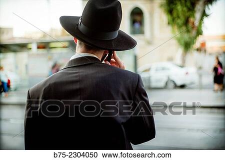 Orthodox Jewish man unrecognizable with hat, seen from the back talking on the phone in Jerusalem, Israel, Middle East View Large Photo Image Stock Image - Orthodox Jewish man unrecognizable with hat, seen from the back talking on the phone in Jerusalem, Israel, Middle East. Fotosearch