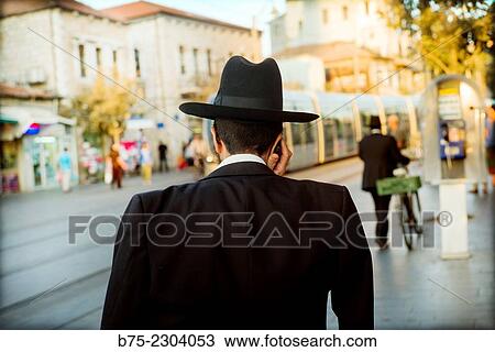 Orthodox Jewish man unrecognizable with hat, seen from the back talking on the phone in Jerusalem, Israel, Middle East View Large Photo Image Stock Image - Orthodox Jewish man unrecognizable with hat, seen from the back talking on the phone in Jerusalem, Israel, Middle East. Fotosearch