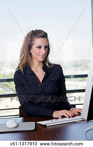 Stock Image - Portrait of a blonde woman at workplace with the computer. Fotosearch
