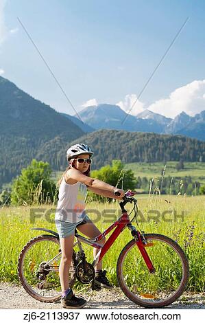 Stock Photo - Portrait of a girl on a bike enjoying summer vacations in beautiful countryside, Bohinj Slovenia.. Fotosearch