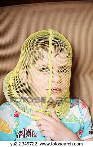Stock Image - Portrait of girl with net covering her face. She looks troubled and pensive. Conceptual image of childhood, boredom and contemplation.. Fotosearch