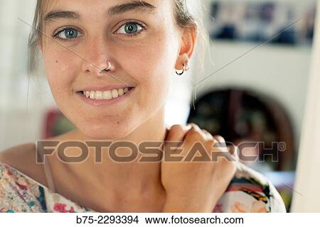 Portrait of young girl with blue eyes and a pierced nose and ear, with a hand on her shoulder, looking at camera with calm and relaxed expression View Large Photo Image Picture - Portrait of young girl with blue eyes and a pierced nose and ear, with a hand on her shoulder, looking at camera with calm and relaxed expression. Fotosearch