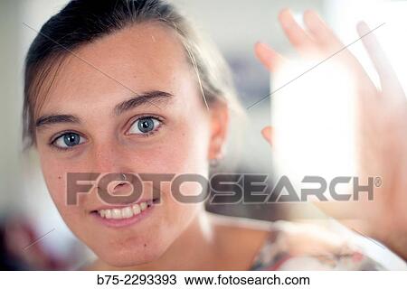 Portrait of young girl with blue eyes and a pierced nose and ear, with one hand on the glass of a window in a calm, relaxed expression View Large Photo Image Stock Image - Portrait of young girl with blue eyes and a pierced nose and ear, with one hand on the glass of a window in a calm, relaxed expression. Fotosearch