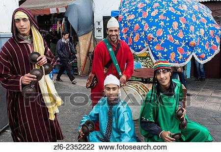 Stock Image - Rabat Morocco main medina young arab boys in band with colorful outfits in outdoor area of medina market.. Fotosearch