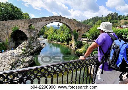 Stock Image - Roman bridge over river Sella, XIVth century, Although known as the Roman bridge, its construction was during the reign of Alfonso XI with its famous stilted arch and two smaller arches are unequal. Fotosearch
