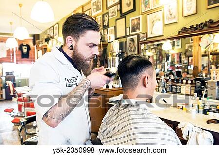 Rotterdam, Netherlands. Barber store Schorem. Barber helping his customer in his barber shop by cutting and modeling his hair. View Large Photo Image Stock Photo - Rotterdam, Netherlands. Barber store Schorem. Barber helping his customer in his barber shop by cutting and modeling his hair.. Fotosearch