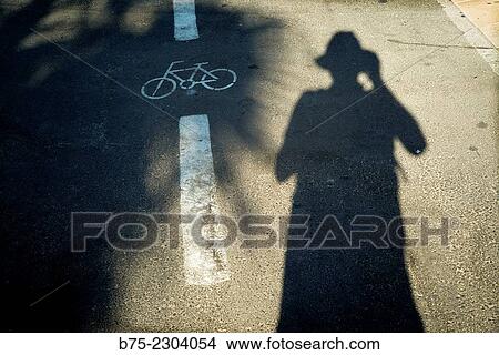 Shadow silhouette of photographer taking a photo of the pavement with a symbol of a bicycle drawn on asphalt, Tel Aviv, Israel, Middle East View Large Photo Image Picture - Shadow silhouette of photographer taking a photo of the pavement with a symbol of a bicycle drawn on asphalt, Tel Aviv, Israel, Middle East. Fotosearch