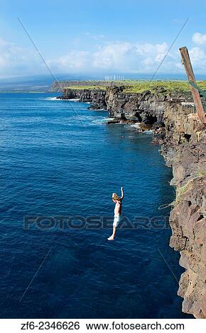 Stock Photograph - South Point Hawaii Big Island cliff pole young man diving intp water danger dangerous dive water MR-2.. Fotosearch