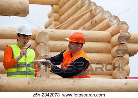 Stock Image - Supervisor and discuss the work plan for a house under construction.. Fotosearch