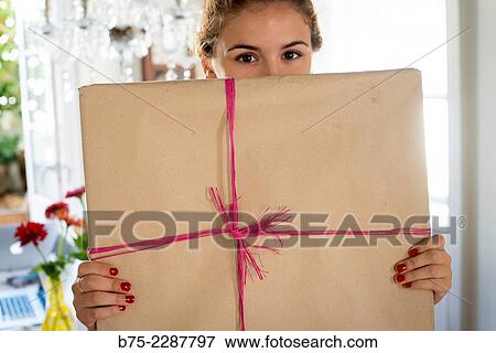 Teen girl with fitness fun looking at the camera half hidden behind a gift package View Large Photo Image Stock Photo - Teen girl with fitness fun looking at the camera half hidden behind a gift package. Fotosearch