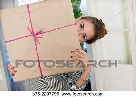 Teen girl with fitness fun looking at the camera half hidden behind a gift package View Large Photo Image Stock Photograph - Teen girl with fitness fun looking at the camera half hidden behind a gift package. Fotosearch