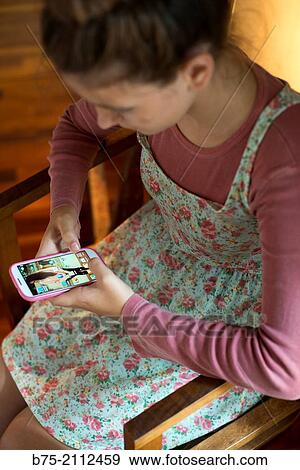 Stock Photo - Teenager girl with a country flowers dress playing with a smart phone.. Fotosearch