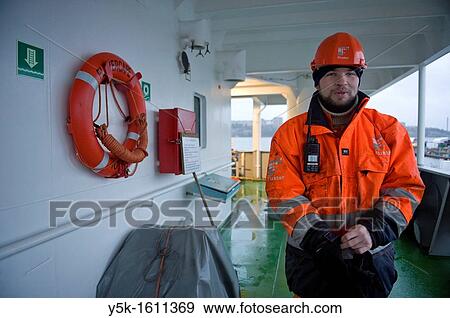 The Russian second officer of container-vessel MV Flintercape on the rear deck of the ship, near the gangway to the docks. It's cold outside, so the man is putting on his gloves. View Large Photo Image Stock Photo - The Russian second officer of container-vessel MV Flintercape on the rear deck of the ship, near the gangway to the docks. It's cold outside, so the man is putting on his gloves.. Fotosearch