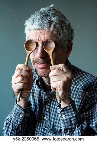Stock Photography - Tilburg, Netherlands. Studio Portrait of a middle aged man, holding two ladle's in font of his eyes.. Fotosearch
