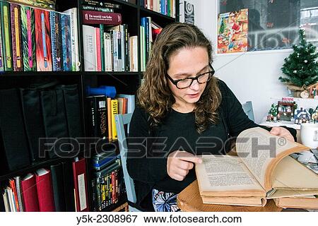 Tilburg, Netherlands. Young, single, and thoughtful woman with her library of books in her living room. View Large Photo Image Stock Photo - Tilburg, Netherlands. Young, single, and thoughtful woman with her library of books in her living room.. Fotosearch