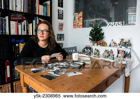 Tilburg, Netherlands. Young, single, and thoughtful woman with her library of books and collection of old black and white photographs. View Large Photo Image Stock Photography - Tilburg, Netherlands. Young, single, and thoughtful woman with her library of books and collection of old black and white photographs.. Fotosearch