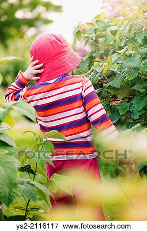 Stock Photo - Tranquil summer scene. Young girl with red hat standing outdoors, watching nature.. Fotosearch