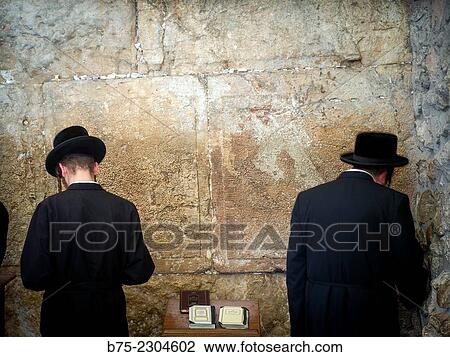 Stock Image - Two unrecognizable jewish man seen from behind, praying in the synagoge in Walling Wall, Western Wall Plaza, Jewish Quarter, Jerusalem, Israel.. Fotosearch