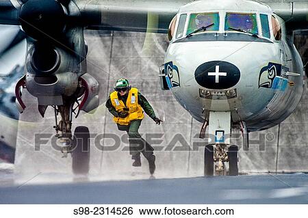 U. S. Navy Seaman Daniel Alt clears the launch path of an E-2C Hawkeye after attaching it to a catapult on the flight deck of the aircraft carrier USS Harry S. Truman in the Atlantic Ocean, Sept. 26, 2014. View Large Photo Image Stock Photograph - U. S. Navy Seaman Daniel Alt clears the launch path of an E-2C Hawkeye after attaching it to a catapult on the flight deck of the aircraft carrier USS Harry S. Truman in the Atlantic Ocean, Sept. 26, 2014.. Fotosearch