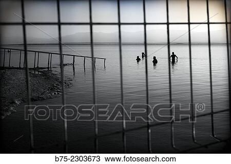 View of Dead Sea, With Jordan at the background, and silhouettes of unrecognizable people bathing early in the morning, seen from behind a fence. Israel, Middle East View Large Photo Image Stock Image - View of Dead Sea, With Jordan at the background, and silhouettes of unrecognizable people bathing early in the morning, seen from behind a fence. Israel, Middle East. Fotosearch