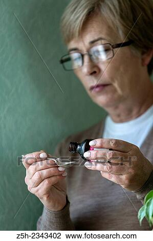 Stock Image - Woman counts drop medication.. Fotosearch