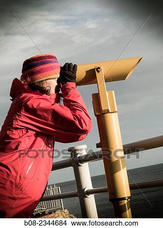 woman in winter clothes looking out to sea through a cliff-top telescope, Robin Hoods Bay, Yorkshire, Britain. View Large Photo Image Picture - woman in winter clothes looking out to sea through a cliff-top telescope, Robin Hoods Bay, Yorkshire, Britain.. Fotosearch
