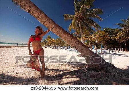 Stock Photography - Woman posing near the tree at the beach, Tulum, Quintana Roo, Yucatan Province, Mexico, Central America.. Fotosearch