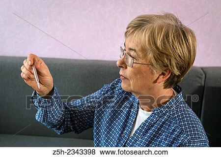 Stock Photo - Woman thermometer measures temperature.. Fotosearch