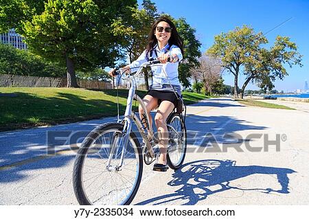 Young Asian American woman rides her bike on Chicago's Lakeshore Trail on a sunny day in Chicago, IL, USA. View Large Photo Image Picture - Young Asian American woman rides her bike on Chicago's Lakeshore Trail on a sunny day in Chicago, IL, USA.. Fotosearch