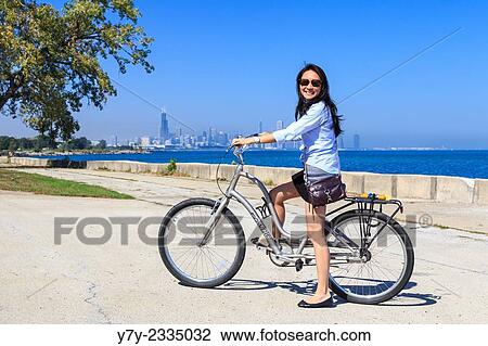 Young Asian American woman rides her bike on Chicago's Lakeshore Trail on a sunny day in Chicago, IL, USA. View Large Photo Image Stock Image - Young Asian American woman rides her bike on Chicago's Lakeshore Trail on a sunny day in Chicago, IL, USA.. Fotosearch