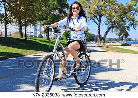Stock Image - Young Asian American woman rides her bike on Chicago's Lakeshore Trail on a sunny day in Chicago, IL, USA.. Fotosearch