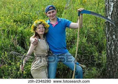 Stock Image - Young couple with an agricultural tool in the field.. Fotosearch
