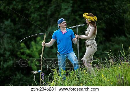 Stock Image - Young couple with an agricultural tool in the field.. Fotosearch