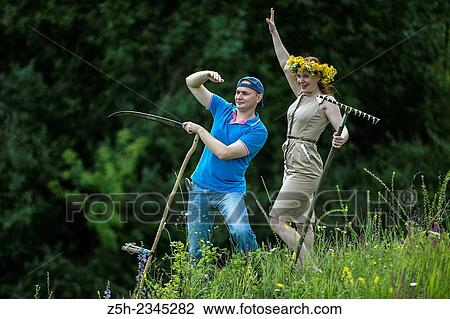 Stock Image - Young couple with an agricultural tool in the field.. Fotosearch